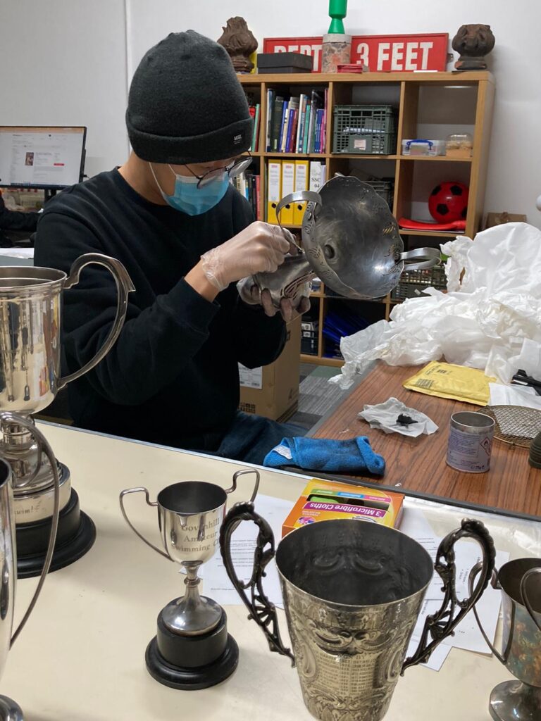 A man cleaning metal trophies with a cloth