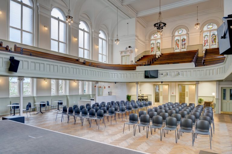 Interior of auditorium at Adelaide Place showing audience space on ground floor and in balcony with stained glass windows